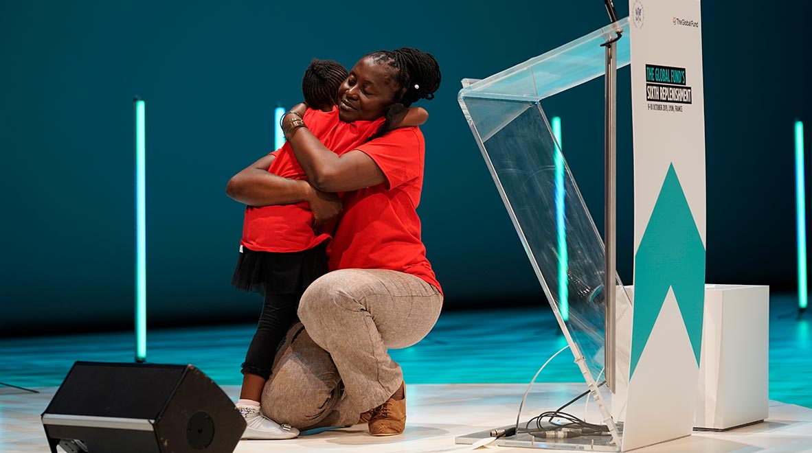 Connie Mudenda, Ambassadrice (RED), enlace sa fille sur la scène de la sixième Conférence de reconstitution des ressources du Fonds mondial à Lyon, en France, le 9 octobre 2019.